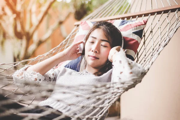 Młoda kobieta słuchania muzyki relaks, leżącego w hamaku w wakacje, vintage tonu. Koncepcja życia — Zdjęcie stockowe