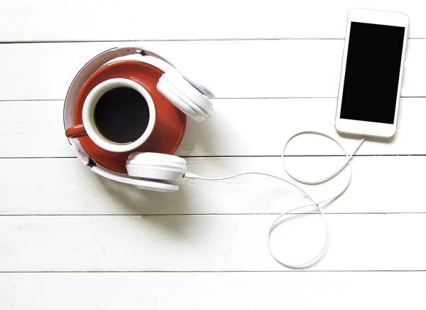 Słuchawki biały i czerwony filiżanka kawy z smart telefonu tabela biały biurko z drewna. Koncepcja muzyki i stylu życia. Widok z góry z miejsca kopii — Zdjęcie stockowe