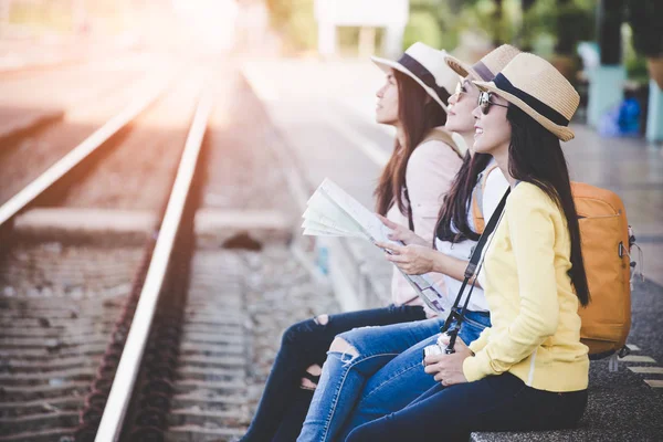 アジア女性旅行者と旅行バックパック地図を押しながら鉄道駅プラットフォームで待っている客のグループ。旅行の概念 — ストック写真
