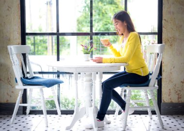 Asyalı kadın kahve dükkanı vintage beyaz masaya kahve içme. Yaşam tarzı kavramı, yumuşak odak