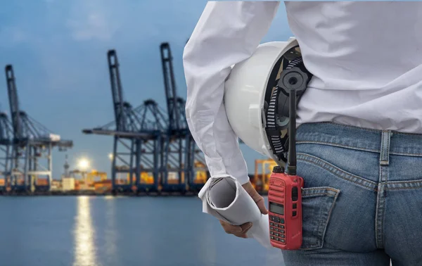 Ingeniera mujer sosteniendo casco blanco y plano con radio para el control de seguridad de los trabajadores en el buque de carga de contenedores de carga para importación logística fondo de exportación. Concepto de Ingeniero —  Fotos de Stock