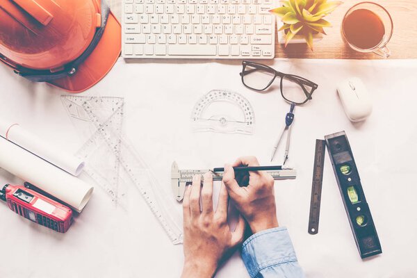 Top View Architect working on blueprint. Рабочее место архитекторов. Инженерные инструменты и управление безопасностью, чертежи, линейка, оранжевый шлем, радио, ноутбук и компас делителя. Концепция строительства
