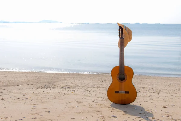 Verão viajando com guitarra e chapéu de mulher de moda na praia de areia no feriado, pôr do sol fundo da praia. Conceito de Verão e Viagem . — Fotografia de Stock