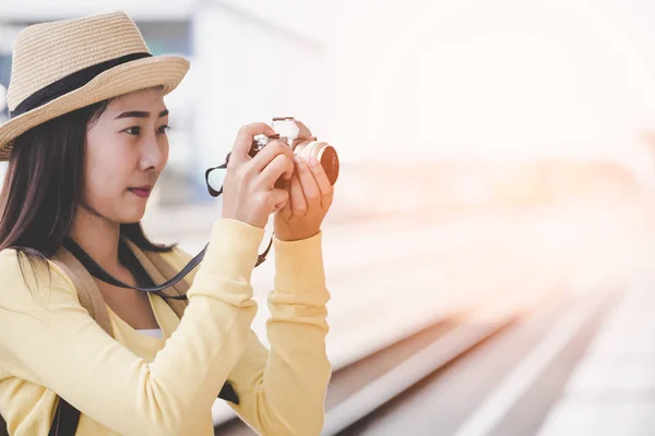 旅行と観光アジアの若い女性は、カメラを持ってのバックパックを身に着けている電車を待って写真を撮る。旅行の概念 — ストック写真