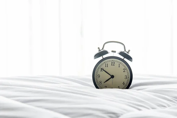 Ceas deșteptător vintage te trezești pe pat alb, foaie, plapumă și pernă dimineața cu o zi însorită. Lifestyle Concept — Fotografie, imagine de stoc