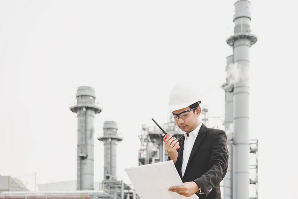 Μηχανικός άνθρωπος που κρατά το λευκό κράνος και σχεδιάγραμμα με radio για τον έλεγχο της ασφάλειας των εργαζομένων στη βιομηχανία ενέργειας του σταθμού. Μηχανικός έννοια — Φωτογραφία Αρχείου