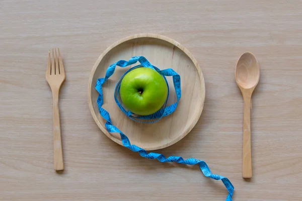 ダイエット痩身グリーンアップルと重量、木製プレートにタップを測定します。ダイエットと健康の概念 — ストック写真