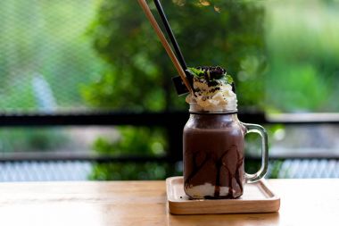 Yaz buz taze içeceği. Hatmi çikolatalı milkshake dondurma ve krema ile servis cam mason kavanoza, yeşil doğa arka plan, kopyalama alanı