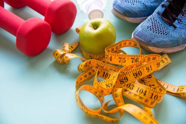 Yeşil elma ile zayıflama kilo diyet ve dokunun ölçme, ağırlık ahşap plaka, sebze, halter, renkli arka plan üzerinde ölçek. Diyet ve sağlıklı kavramı