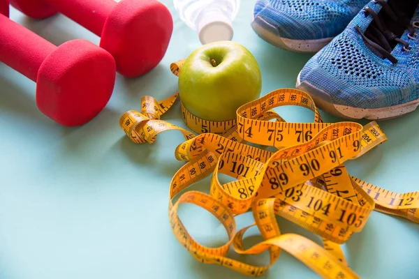 Diet slimming weight with green apple and measuring tap, scale weight on the wood plate, vegetables, dumbbells, colourful background.  Diet and Healthy Concept