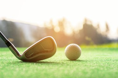 Asyalı kadın Golf oyuncu swing golf topu yeşil günbatımı olay zamanında vurdu vurdu. Sağlıklı yaşam konsepti.