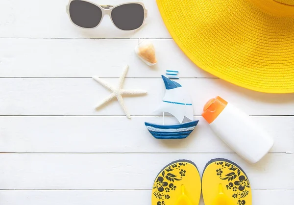 Yaz modası sarı büyük şapka ve plaj aksesuarları. Tropikal deniz. Olağandışı üstten görünüm, ahşap beyaz arka plan. Yaz konsepti.