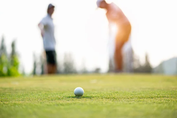 Golf topu yaklaşım tutun yeşil. Kaç oyuncu koyarak golf topu arka planda golf. Yaşam tarzı kavramı.