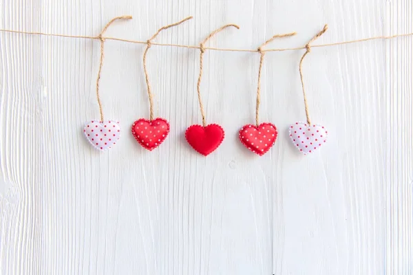 Valentine Day  Sewed pillow hearts row border on red and white clothespins at rustic white wood planks. Happy lovers day card mock up, copy space.  Valentine Concept