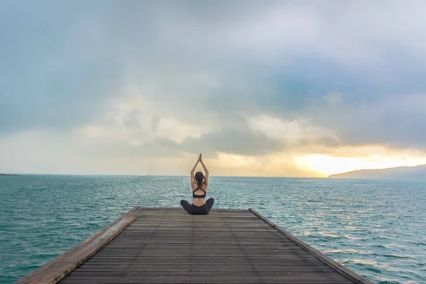 健康的妇女生活方式平衡练习冥想和能量瑜伽在木桥梁早晨海滩 健康理念 — 图库照片