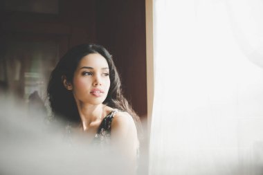 Güzel genç kadın yanındaki pencere perde arkasında sabah vintage sesi arıyor. Yaşam tarzı ve kavram rahatla.