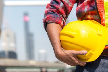 Sarı kask tutan mimar çalışan bir işçi güvenlik denetimi şehir sitesi için. 