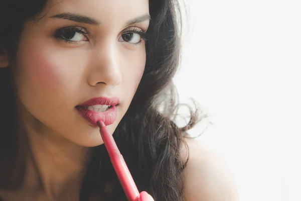 Beautiful luxury young woman applying lip liner to nude red lips. Close up shot and make up cosmetic of woman putting lipstick on her lip