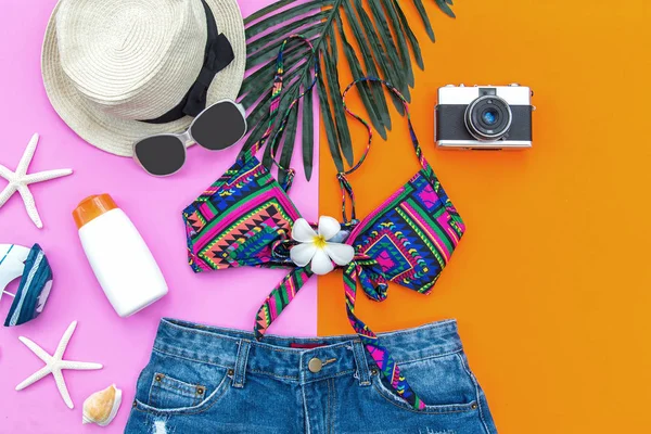 夏季时尚女装泳装比基尼 照相机 防晒霜 太阳眼镜 假期旅行和假期 紫色和粉红色的背景 暑期理念 — 图库照片