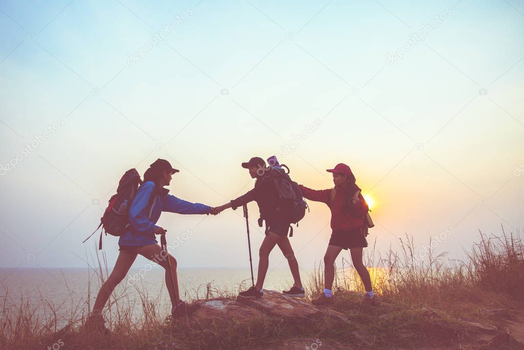 Teamwork hiker women helping her friend climb up the last section of sunset in mountains.  Traveler teamwork in outdoor lifestyle adventure and camping.  Travel Concept.