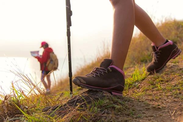 Close up shoe hiker.  Group young women of hikers walking with backpack on a mountain at sunset.  Traveler check mapping for going camping.  Travel Concept