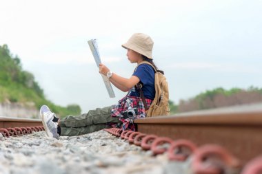Çocuk Asyalı kız tutan demiryolu içinde oturan kamera ve seyahat sırt çantaları ile eşleştirir. Seyahat kavramı
