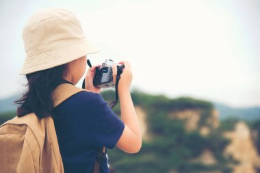Mutlu beyaz çocuk Asyalı kız sırt çantası gülümseyen ve kamera için tutarak fotoğraf çek dağda alıyor. Seyahat kavramı.
