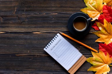 Yeni Yıl Kararları Kavramsal. Mevsimlik sonbahar akçaağaç yaprakları. Sıcak kahve buharı tüten sıcak bir eşarp ve tahta masa arkaplanındaki tebrik mesajı için kağıt bir not. Güneşli bir günde rahatla. Yaşam tarzı kavramı