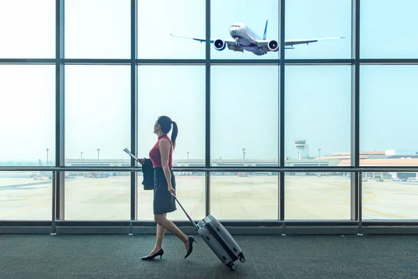 Business asian women leave luggage and meet at the airport to fly to see work in foreign countries.  People holding passport and sitting for wait the airplane at the airport glass window for destination leisure.  Business and Trips Concep