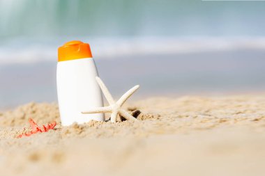 Koruyucu güneş kremi ya da güneş kremi ve beyaz plastik şişeli, tropikal plajda deniz yıldızı olan sağlıklı ciltli kadın için güneş kremi, tatilde yaz aksesuarları, metin için kopyalama alanı. Yaz Konsepti