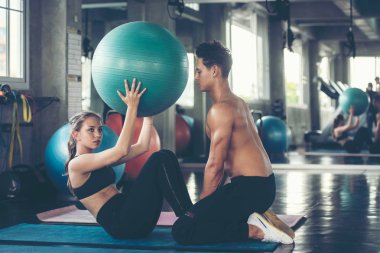 Yoga topunu eğiten antrenör, spor salonunda bir kadınla vücut zayıflığı ve sağlıklı bakımı için egzersiz yapıyor. Beden eğitimi eğitmeni müşterileriyle spor yapıyor. Sağlıklı Spor Konsepti