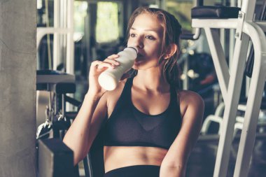 Spor salonunda egzersiz yaptıktan sonra vücut bakımı ve zayıflığı için protein sütü içen yaşam tarzı kadınları. Fitness eğitmeni, spor yapıyor. Diyet ve Sağlıklı Spor Konsepti