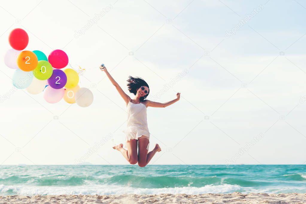 Asian young woman happy  jumping with balloon congratulation and celebrate in Happy New year 2020 for change new life future concept. Freedom lifestyle jump as part of Number 2020 success on the sand beach outdoor.  Vintage Tone