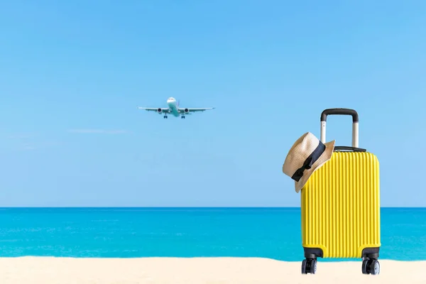 Summer travel and plan with yellow suitcase luggage in the sand beach. Travel in the holiday trips, airplane and blue sky background. Summer and Travel Concept