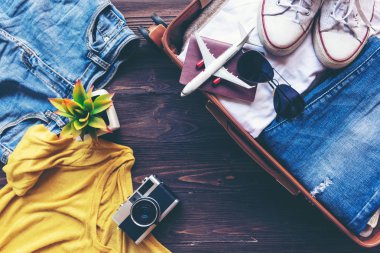Tatil gezisinde günlük kadın kıyafetleri ve kamerayla ahşap masa üzerinde seyahat planlamak için Top View Open vintage bavulu. Yazın Yaz ve Seyahat Konsepti