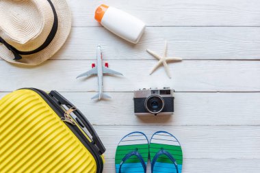 Top View Yaz Seyahati ve Planı. Aksesuar modasında sarı bavul, eski kamera, tatil gezilerinde ahşap beyaz arka planda güneş kremi. Yaz ve Seyahat Konsepti
