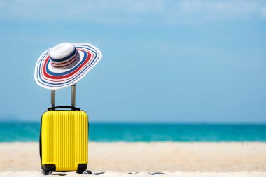 Yaz seyahati ve kumsalda sarı valizli planlar. Tatil gezileri, uçaklar ve mavi gökyüzü arka planında seyahat. Yaz ve Seyahat Konsepti