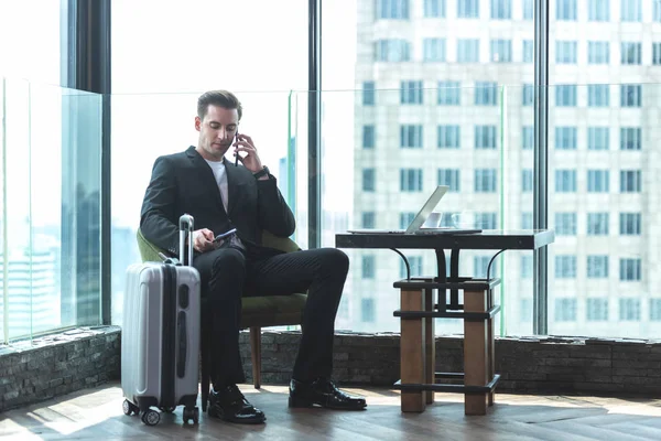 Businessmen leave luggage and meet at the airport to fly to see work in foreign countries.  People holding passport and sitting for wait the airplane at the airport glass window for destination leisure.  Business and Trips Concept