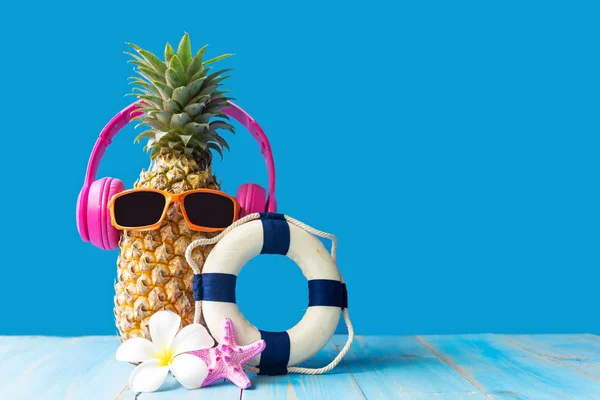 Summer in the party.  Hipster Pineapple Fashion in sunglass and music bright beautiful color in holiday, Creative art fruit for tropical style on the beach vibes, blue background.  Fashion Summer Vacation Concept