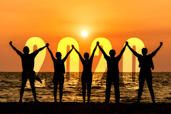Silhouette happy business teamwork raise hands congratulation and celebrate in Happy New year 2020 for change new life future concept. Freedom lifestyle group people team jump as part of Number 2020 success at the sunset beach outdoo