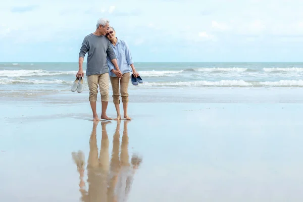 亚洲老两口快乐地在海滩上散步 拥抱和放松 老年旅游家庭度假和夏季退休后的休闲和活动 — 图库照片