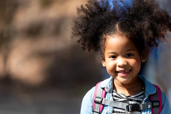 Happy little smiling African girl having fun at the part outdoor for back to school