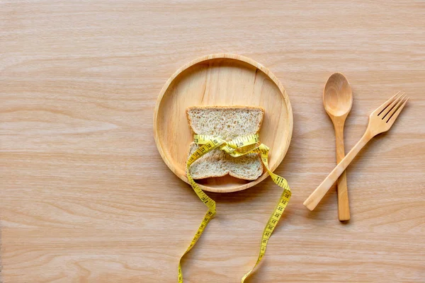 板の上でパンや測定テープを痩身重量のため 食事と健康の概念 — ストック写真