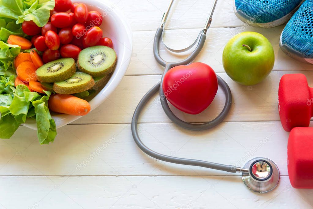 Healthy lifestyle for women diet medical stethoscope with heart shape and dumbbells sport equipment, sneakers, measuring tape, fruit healthy green apples on white wooden background.  Healthy Concept.