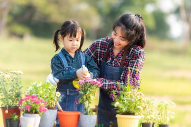 Aile kızı, annesinin bahçeye çiçek dikmesine yardım ediyor. Gençler anne ve kızı bahçeyle uğraşıyorlar. Güneşli doğa geçmişi. Bahar ve yaz günlerinde mutlu ve keyifli. Aile Kavramı