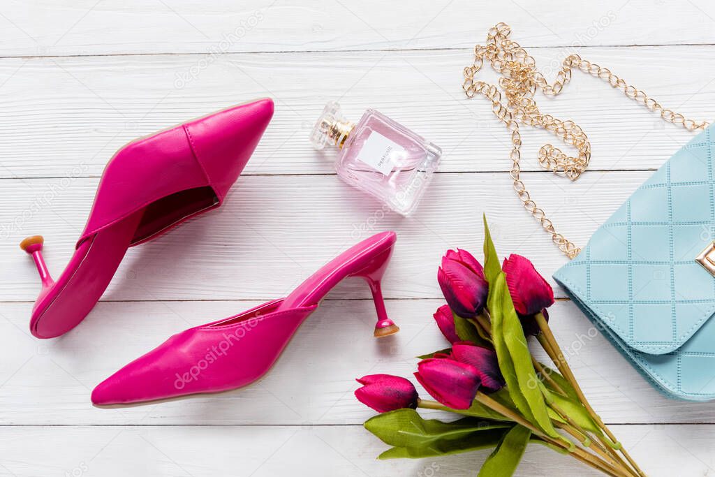 Fashion bag and shoe woman accessories background. Trendy fashion luxury handbag, heels shoe, perfume and cosmetic design with pink tulip flower. Lifestyle and Beauty Concept