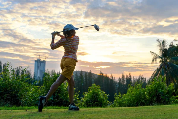 Golfer sport course golf ball fairway.  People lifestyle woman playing game golf tee of on the green grass sunset background.  Asia female player game shot in summer.  Healthy and Sport outdoor