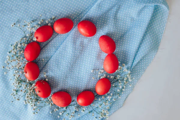 Mavi arka planda boyanmış Paskalya yumurtaları. bahar arkaplanı çiçekler ve yumurtalar üst görünüm düz yatıyordu