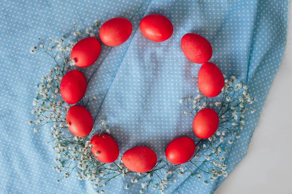 Mavi arka planda boyanmış Paskalya yumurtaları. bahar arkaplanı çiçekler ve yumurtalar üst görünüm düz yatıyordu