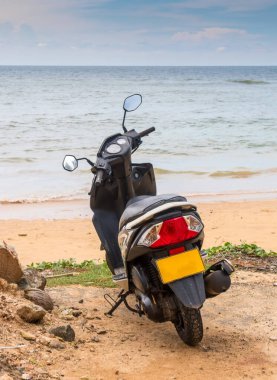Uçsuz bucaksız okyanusun kumlu kıyısında yalnız scooter, Sri Lanka